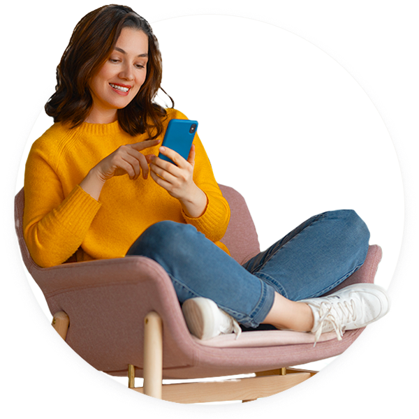 Une jeune femme est sur son téléphone et assise en tailleur.