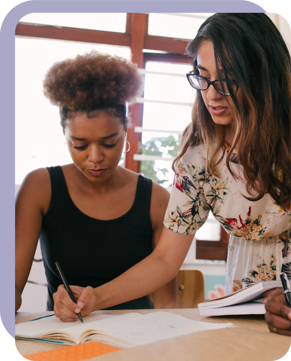 Deux jeunes femmes au travail écrivent quelque chose dans un carnet.