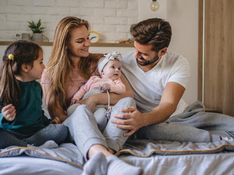 Une famille avec deux jeunes enfants assis sur le lit