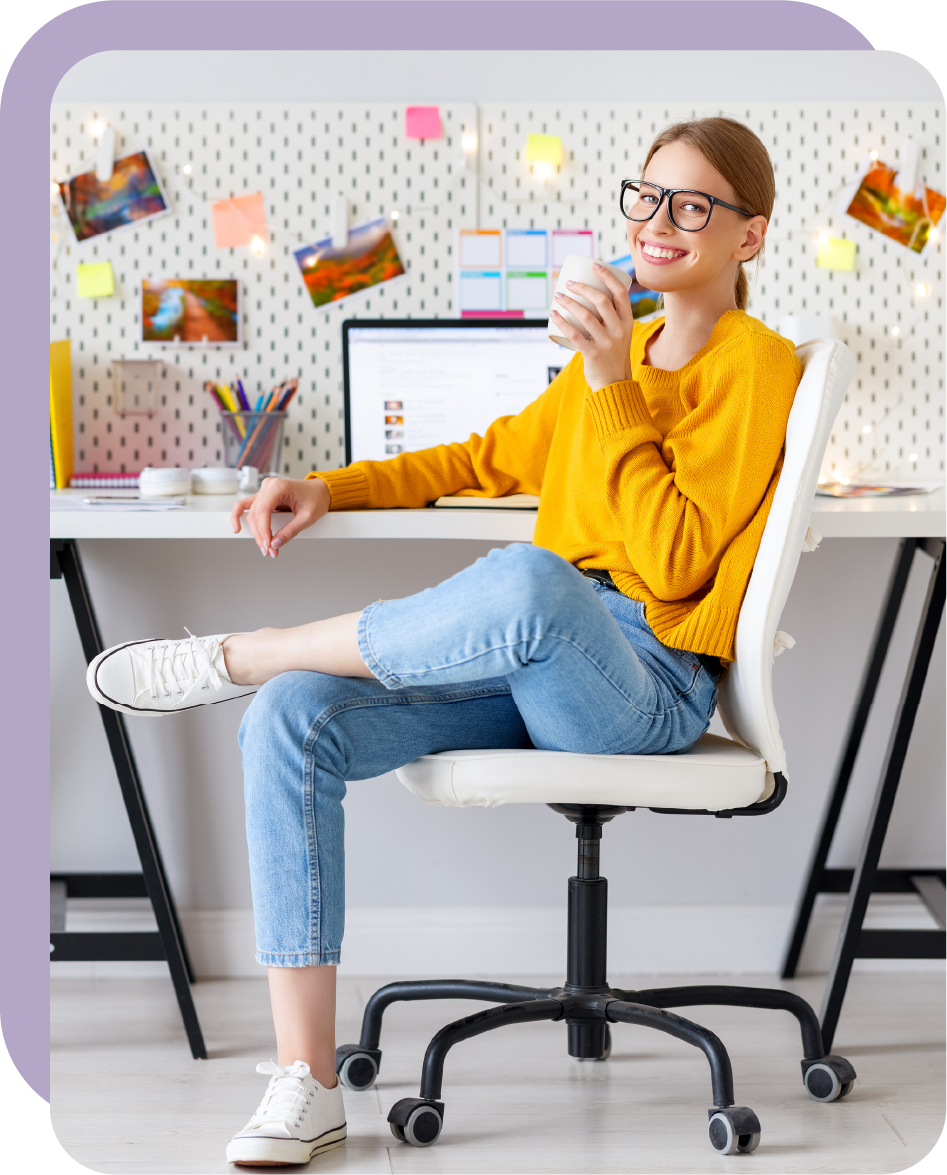 Une jeune femme souriante est assise au bureau et boit du café.