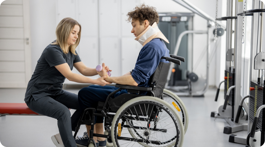 Un homme en fauteuil roulant avec minerve fait des exercices avec une femme en uniforme médical. L'arrière-plan est une salle de sport.