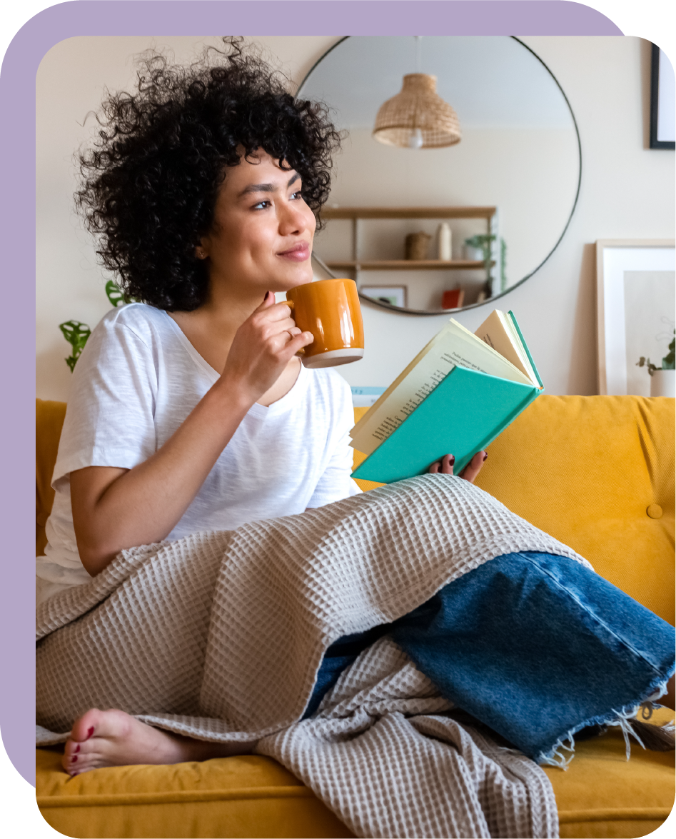 Una donna beve caffè e legge un libro.